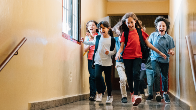 Skolēni laimīgi skrien pa skolas gaiteni