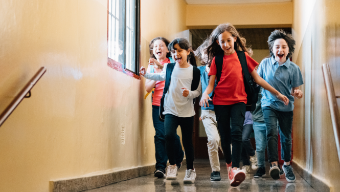Skolēni laimīgi skrien pa skolas gaiteni