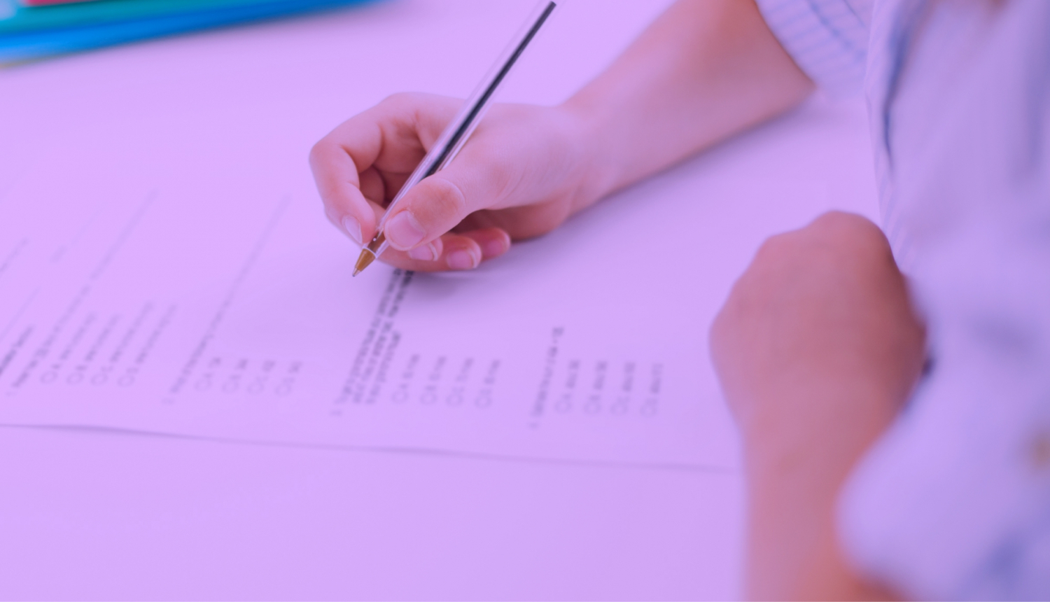Ilustratīvs attēls - roka ar pildspalvu, tiek pildīts eksāmens.